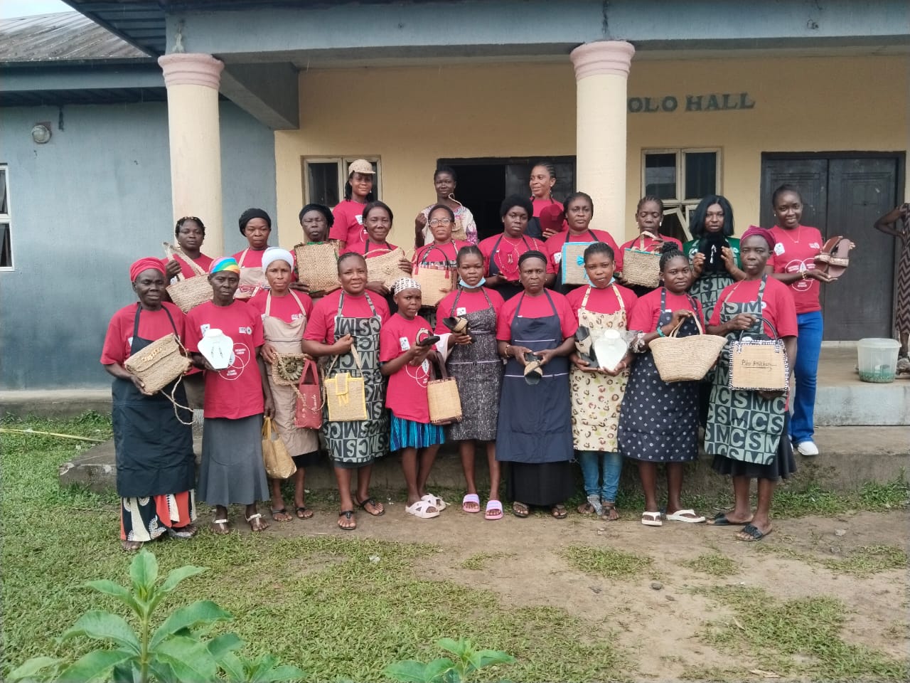 Group of women in front of building each holding up a bag.