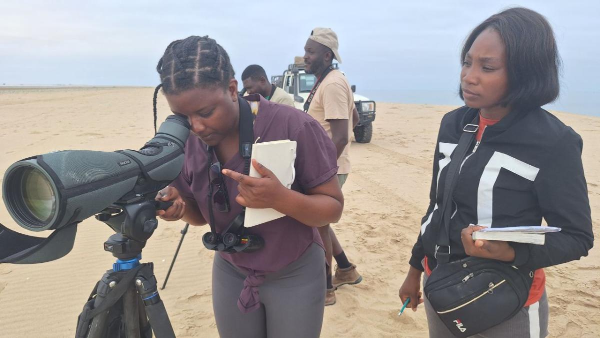 Two women with birdwatching gear and notepads in the field.