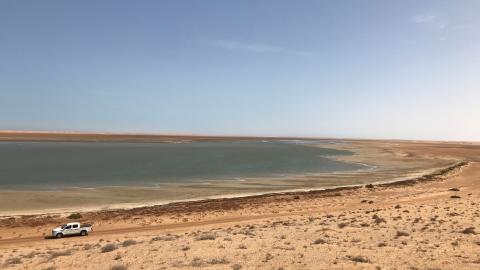 Wide view of the coastal landscape of the Banc d‘Arguin, with a shallow lagoon bordered by sandy shores.