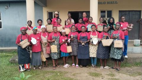 Group of women in front of building each holding up a bag.
